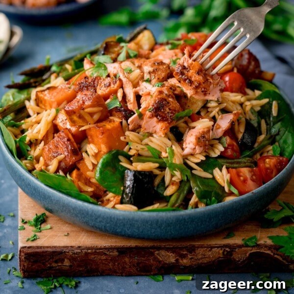 Crispy Lamb Salad with Lemon Mint Dressing 10 A blue bowl full of orzo pasta salad with salmon on a wooden chopping board.