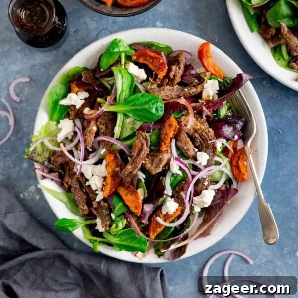 Crispy Lamb Salad with Lemon Mint Dressing 11 A white plate filled with crispy lamb salad with tomato, feta and red onion.