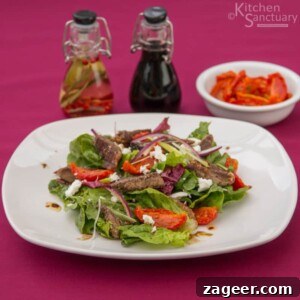 Crispy Lamb Salad with Lemon Mint Dressing 15 white plate with lamb, tomato and feta salad. Oil and vinegar in background next to a small bowl of sun blush tomatoes