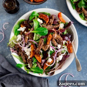Crispy Lamb Salad with Lemon Mint Dressing 8 A white plate filled with crispy lamb salad with tomato, feta and red onion.