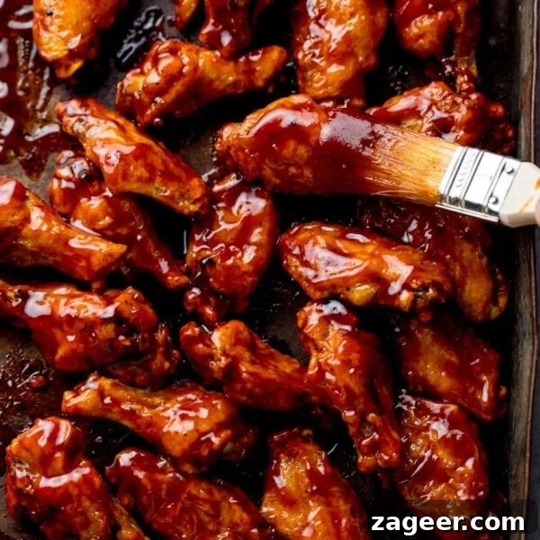 Crispy Garlic Parmesan Chicken Wings Recipe 15 BBQ chicken wings on a tray with BBQ sauce being brushed on