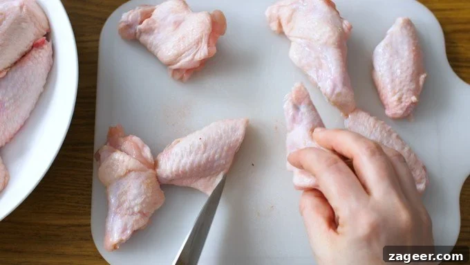 Crispy Garlic Parmesan Chicken Wings Recipe 6 Chicken wings being cut into two pieces on a white chopping board