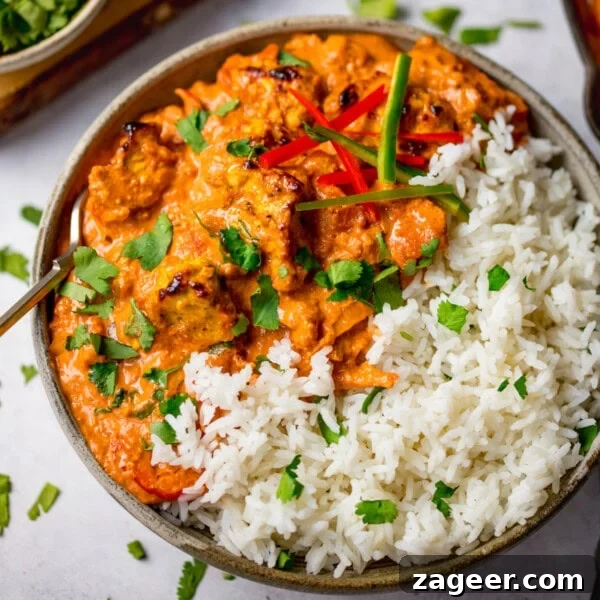Authentic Thai Beef Massaman Curry Recipe for Home Cooking 10 A bowl of chicken tikka masala with white rice, garnished with chopped coriander and sliced chilli peppers.