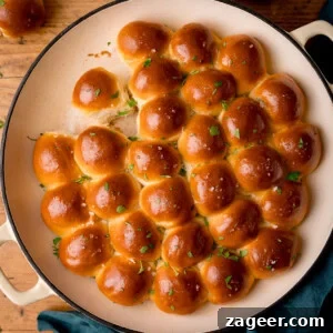 How to Make Soft, Chewy Dough Balls for Any Recipe 12 Golden, shiny dinner rolls arranged closely in a circular baking dish.