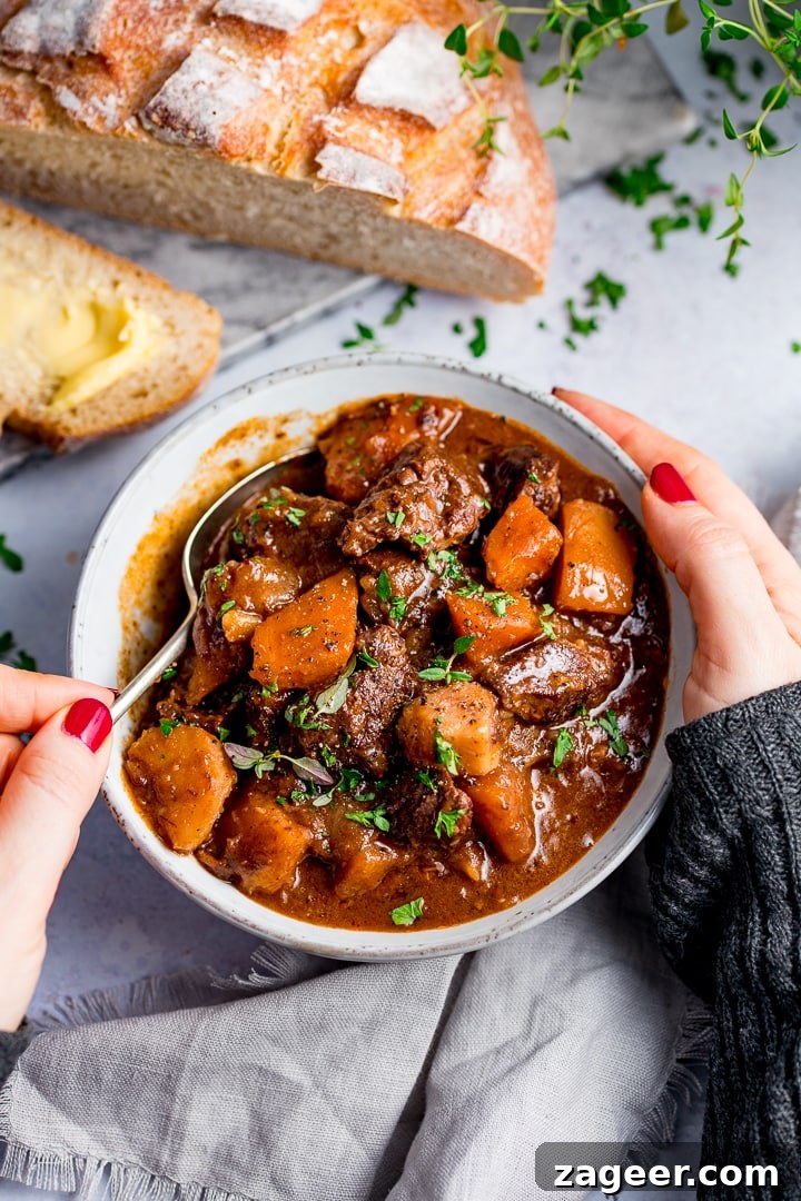 Slow-Cooked Scottish Beef Stew Recipe for Rich, Hearty Flavor 2 Hands around a bowl of Scottish beef stew. A spoonful being taken,