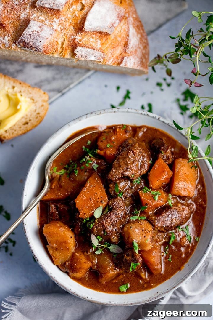 Slow-Cooked Scottish Beef Stew Recipe for Rich, Hearty Flavor 7 Bowl of Scottish beef stew with a spoon in it. Bread in the background.