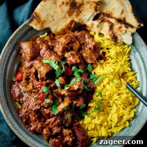Authentic Lamb Rogan Josh Recipe: Flavorful Kashmiri Curry 11 A square, overhead image of lamb rogan josh, in a light blue bowl with brown stripes.