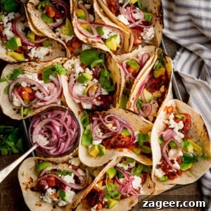 Spicy Black Bean Tacos with Fresh Salsa and Lime 10 A tray of spicy bean tacos filled with avocado, cheese, red onions, and greens.