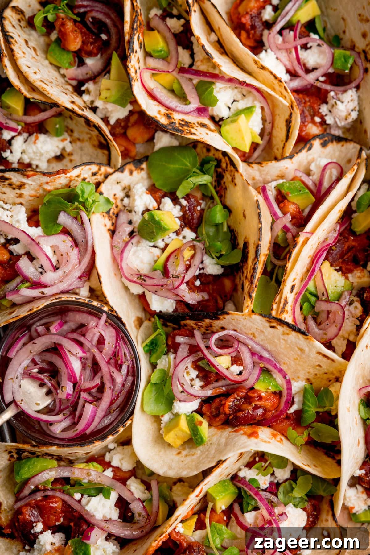 Spicy Black Bean Tacos with Fresh Salsa and Lime 7 A close-up overhead shot of multiple spicy bean tacos filled, avocado, pickled red onions, feta, and watercress all beautifully arranged on a platter.
