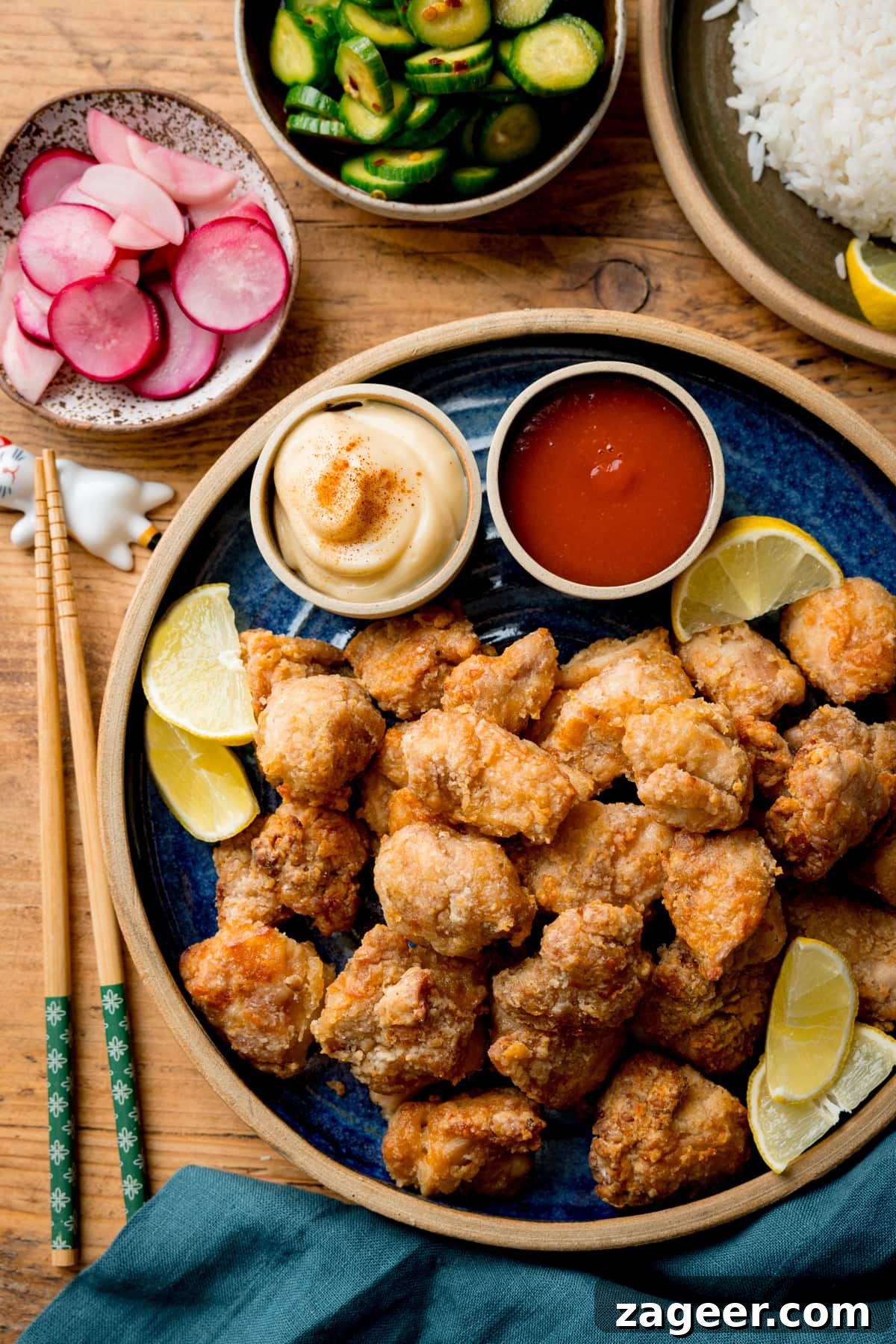 Crispy Air Fryer Chicken Karaage Recipe for Authentic Japanese Flavor 2 A plate of Air Fryer Chicken Karaage with lemon wedges, served with mayonnaise, sriracha, pickled radishes, cucumber salad, and a side of white rice.