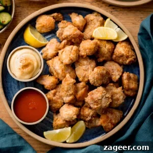 Crispy Air Fryer Chicken Karaage Recipe for Authentic Japanese Flavor 12 A plate of Air Fryer Chicken Karaage bites served with lemon wedges, mayonnaise, and red dipping sauce on a blue plate.