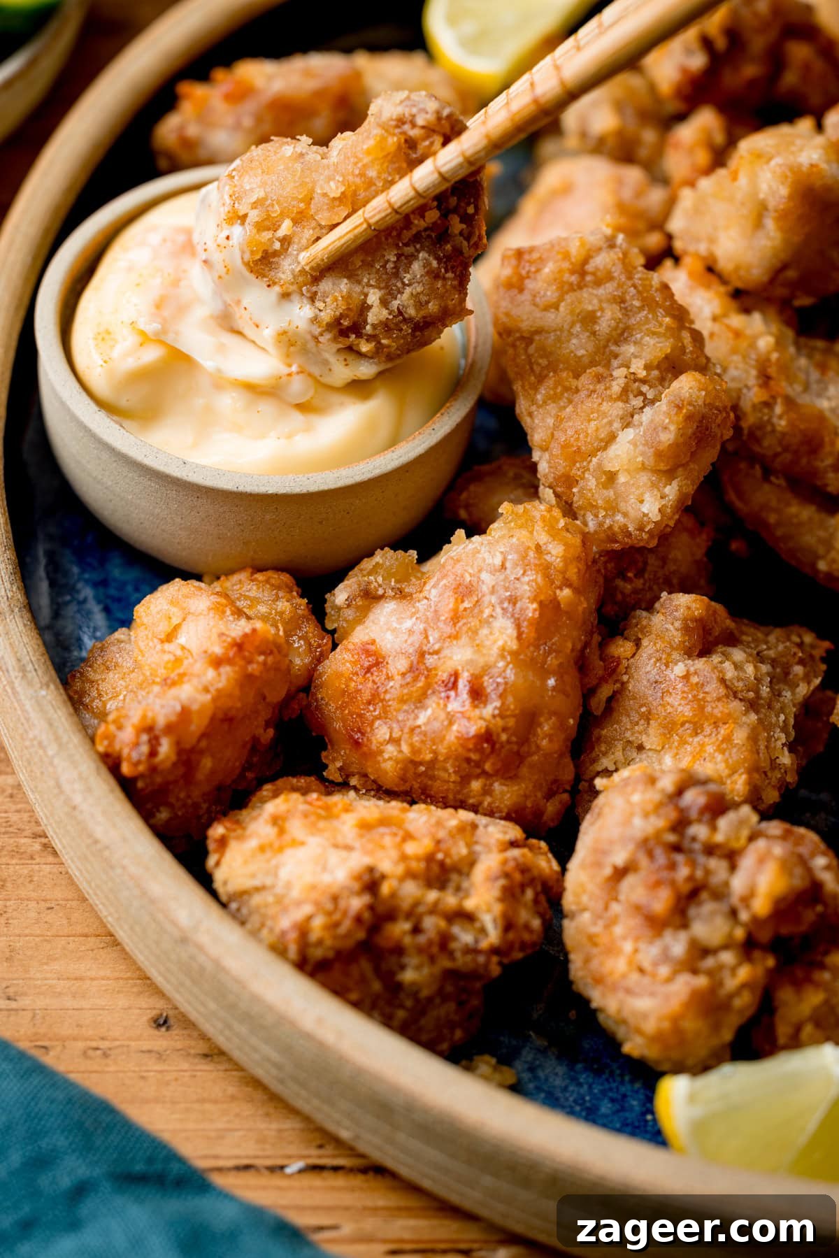 Crispy Air Fryer Chicken Karaage Recipe for Authentic Japanese Flavor 4 A close-up of Air Fryer Chicken Karaage pieces on a plate, with one piece being dipped into kewpie mayonnaise using chopsticks.