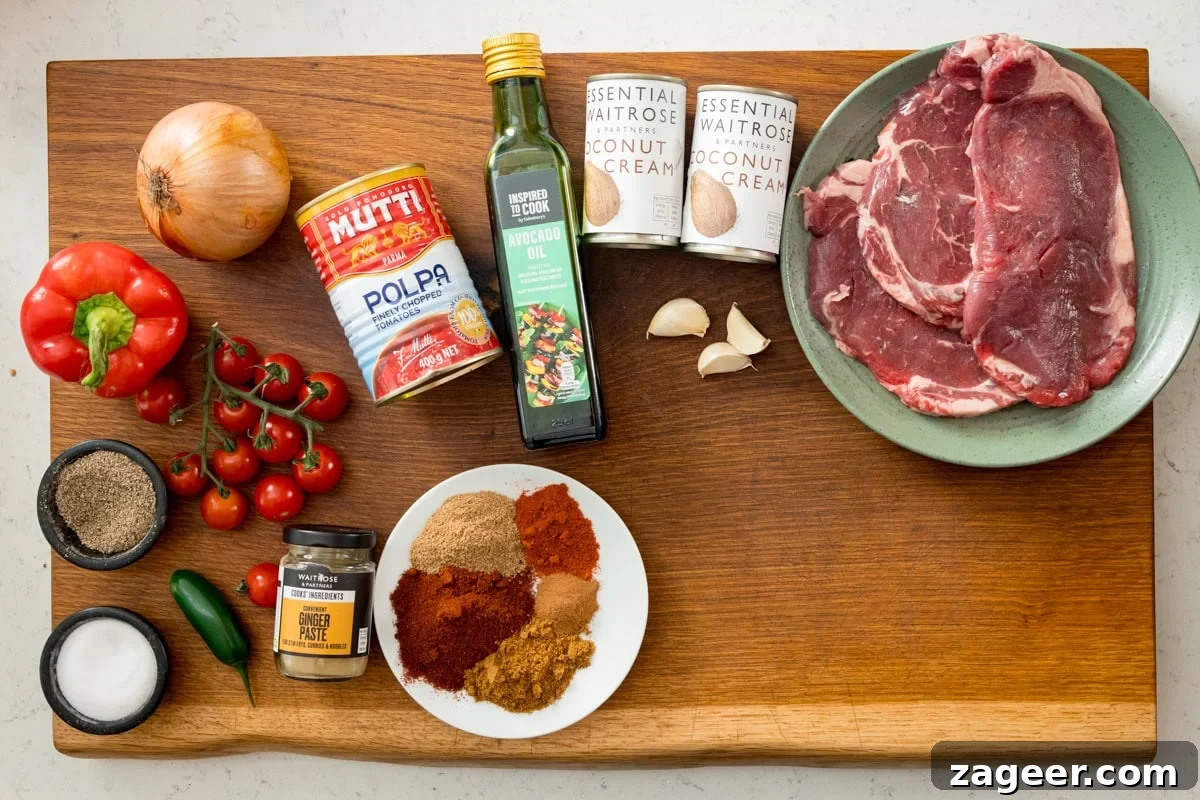 Flavorful Beef Curry Recipe: Simple Steps for Rich Homemade Curry 3 A wooden board with ingredients for a quick steak curry: raw steaks, tinned tomatoes, coconut cream, onion, red pepper, cherry tomatoes, spices, avocado oil, ginger paste, garlic, and a green chilli.
