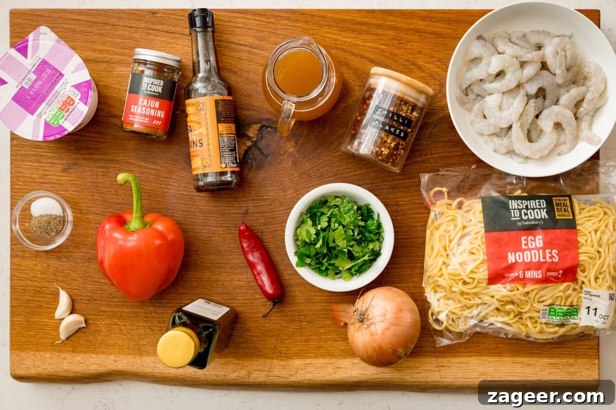 Spicy Cajun Shrimp Noodles with Garlic Butter Sauce 3 Ingredients for a Spicy Prawns with noodles on a wooden board. This includes: king prawns, egg noodles, red pepper, chilli, garlic, onion, coriander, seasonings and stock.