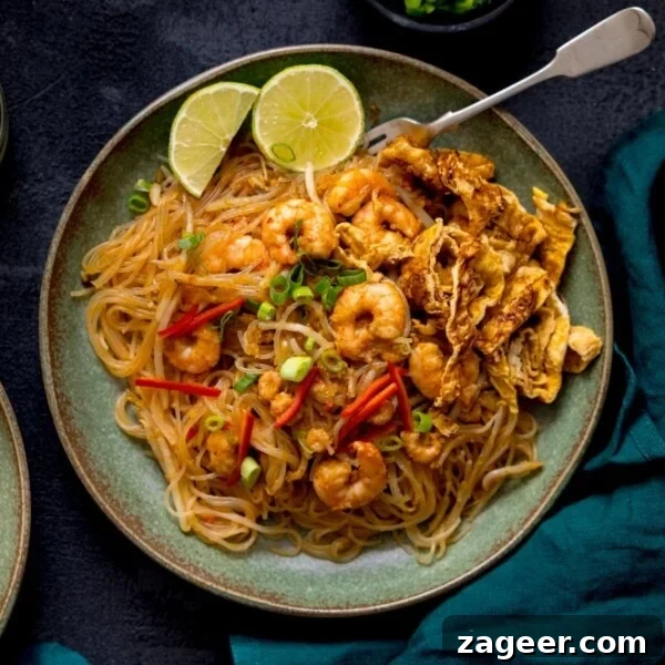 Spicy Cajun Shrimp Noodles with Garlic Butter Sauce 8 Square image of Mee Siam fried noodles on a green plate on a dark background.