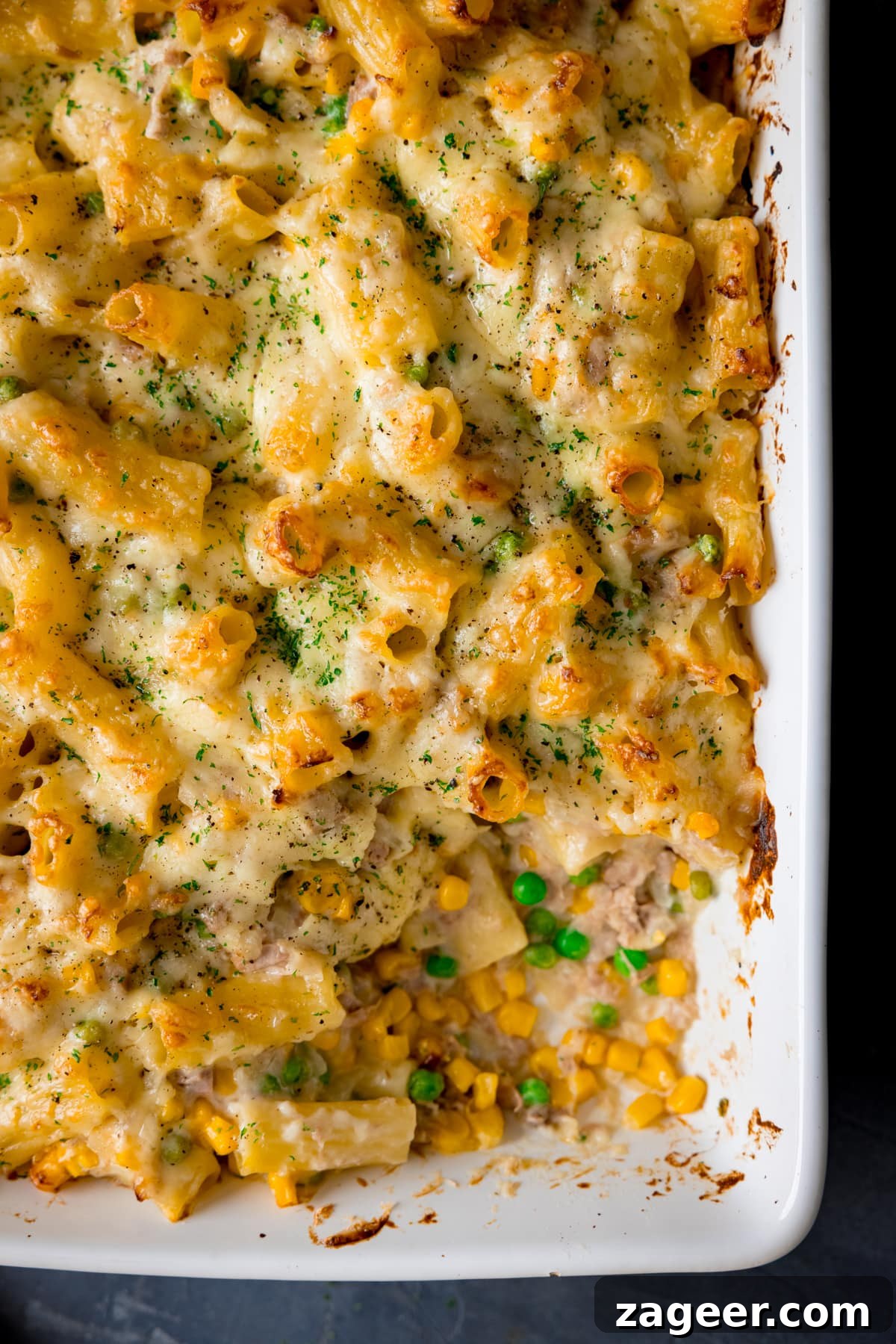 Creamy Tuna Pasta Bake with Cheesy Golden Crust 2 Overhead image of creamy tuna pasta bake in a white dish with a scoopful taken out.