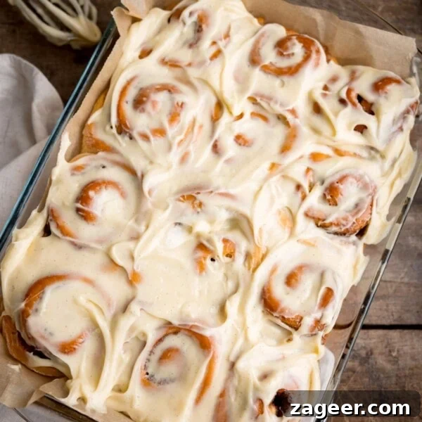 Cinnamon French Toast Recipe: Crispy, Custardy Morning Toast 8 Overhead square image of 12 cinnamon rolls in a baking dish, topped with cream cheese frosting.