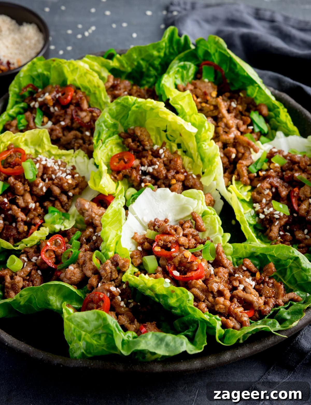 Turkey Lettuce Wrap Recipe: Flavorful Low-Carb Meal Ideas 2 A plate of turkey mince lettuce wraps filled with seasoned meat, topped with sliced red chillies, chopped spring onions, and sesame seeds.
