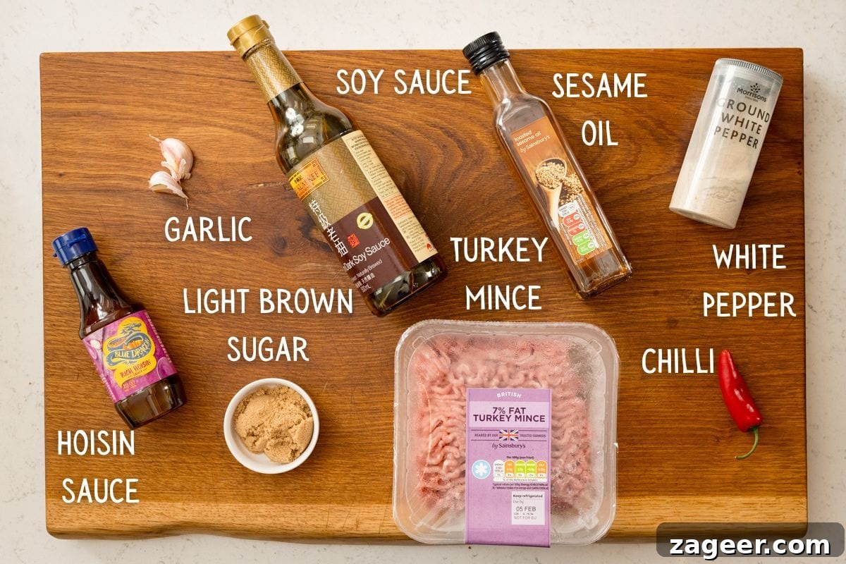 Turkey Lettuce Wrap Recipe: Flavorful Low-Carb Meal Ideas 3 A wooden board holds turkey mince for turkey lettuce wraps, soy sauce, hoisin sauce, light brown sugar, garlic, sesame oil, white pepper, and a red chilli, each labelled with text.