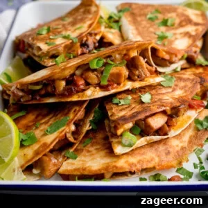 A plate of grilled Chicken Quesadilla filled with diced chicken, vegetables, and melted cheese, garnished with chopped coriander and lime wedges.