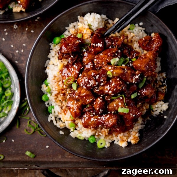 Crispy Chilli Beef in the Air Fryer: Quick Spicy Recipe 11 Square image of air fryer sesame chicken served on a bed of egg fried rice in a black bowl.