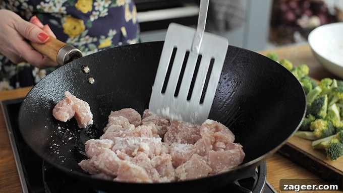 Chicken coated in cornflour, frying in a wok