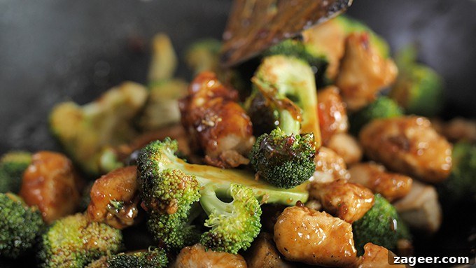 close up of asian crispy chicken and broccoli being stirred in a wok