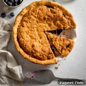 15 Cozy Autumn Baking Ideas for Weekend Treats 8 Overhead picture of a blueberry crumble pie with a piece taken out.