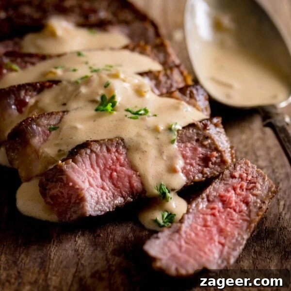 Steak Fries with Creamy Peppercorn Sauce 6 Sliced, cooked steak with diane sauce drizzled over the top on a wooden table with a silver spoon