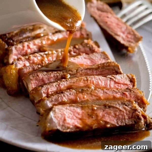 Steak Fries with Creamy Peppercorn Sauce 9 Sliced and cooked steak with red wine jus being poured over the top from a white jug