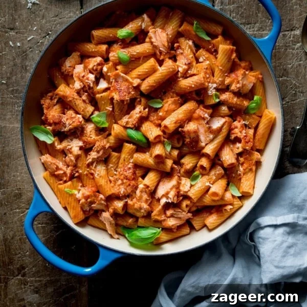Tuscan Salmon with Creamy Lemon Orzo Recipe 12 Square image of rigatoni and salmon in creamy tomato sauce in a blue cast iron pan on a wooden table.