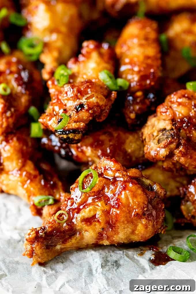Sticky Crispy Asian-Style Chicken Wings Recipe 2 Close up picture of Sticky and Crispy Asian Chicken Wings glistening in the light stacked up on grease proof paper.