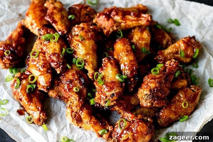 Sticky Crispy Asian-Style Chicken Wings Recipe 4 Overhead picture of Sticky and Crispy Asian Chicken Wings stacked up on grease proof paper.