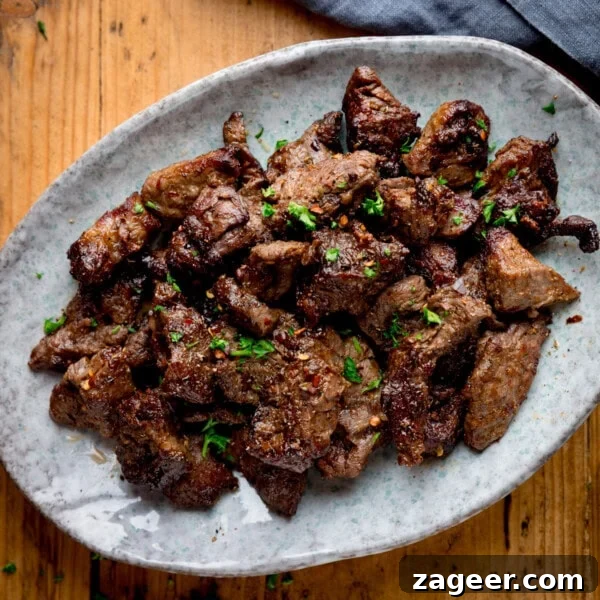 Spicy Gochujang Cream Pasta Recipe You’ll Love 8 A plate of cooked, seasoned air fryer steak pieces garnished with chopped herbs.