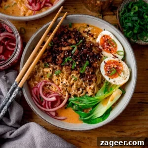 Spicy Pork Curry Ramen Recipe for Bold Flavor 10 A bowl of spicy pork coconut curry ramen with sliced boiled eggs, pak choi, pickled onions and spring onions. There are a set of chopsticks resting o the bowl.