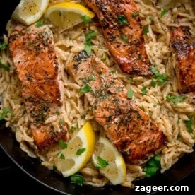 11 Fresh Spring Dinners Ready in 30 Minutes or Less 12 Square image of pan-fried salmon fillets nestled in a bed of creamy lemon orzo topped with parsley. There are lemon wedges at the edges of the pan.
