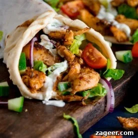 11 Fresh Spring Dinners Ready in 30 Minutes or Less 13 side shot of chicken gyros rolled up in a flatbread with lettuce, tomato, red onion and tzatziki. The gyros is on a dark wooden board with further ingredients scattered around.