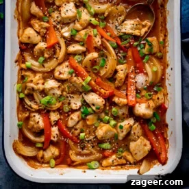11 Fresh Spring Dinners Ready in 30 Minutes or Less 8 Overhead of a chicken 'stir fry' traybake with diced chicken, sliced red peppers, onions, spring onions, sesame seeds and sauce in a white dish.