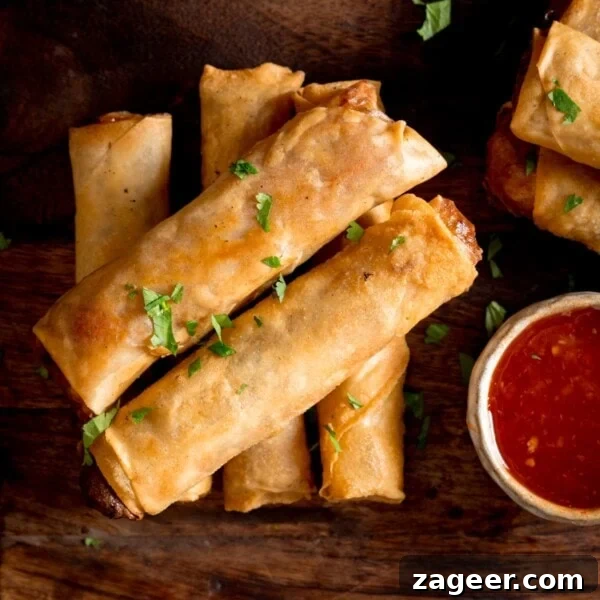 Authentic Chinese-Style Beef Curry Recipe for Home Cooking 8 Overhead picture of a stack of 5 cooked vegetable spring rolls on a wooden board with a small pot of sweet chilli sauce.