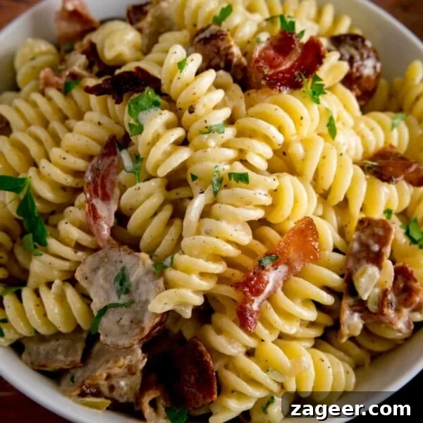 One-Pot Chicken and Broccoli Pasta Dinner in 30 Minutes 11 Overhead image of creamy pasta with sausage and bacon in a white bowl.