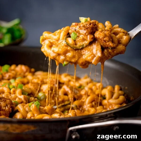 One-Pot Chicken and Broccoli Pasta Dinner in 30 Minutes 9 A spoon lifts cheesy Buffalo Chicken Macaroni Cheese from a frying pan.