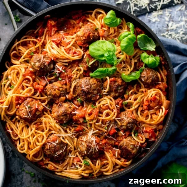 One-Pot Turkey Meatballs with Zucchini Noodles (Courgetti) 8 Spaghetti and meatballs in a black pan, topped with grated cheese and fresh basil, served with rich sauce.