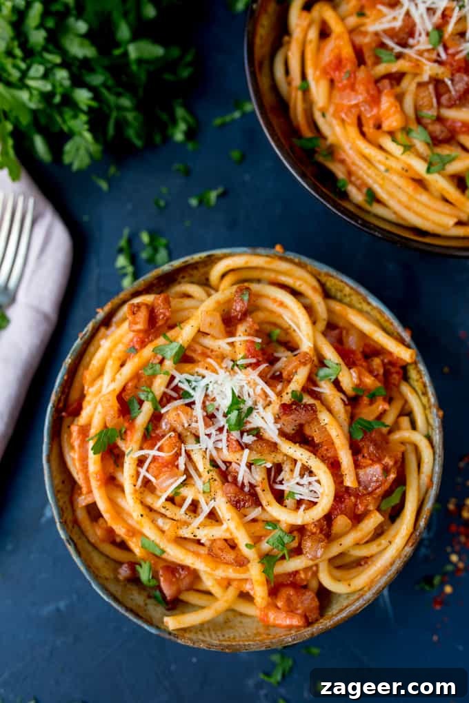 Authentic Amatriciana Pasta Recipe: Classic Roman Sauce Guide 3 Overhead photo of a bowl of Amatriciana on a blue background