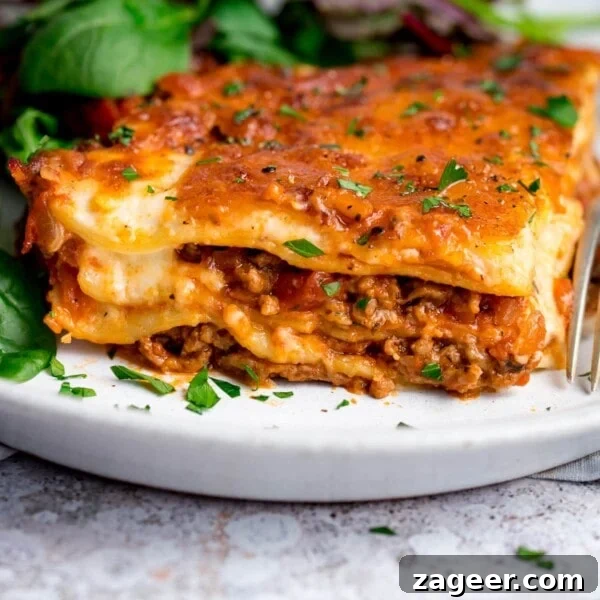 Classic Slow-Cooked Beef Ragu Recipe for Pasta and Polenta 9 Portion of lasagne on a white plate with salad in the background