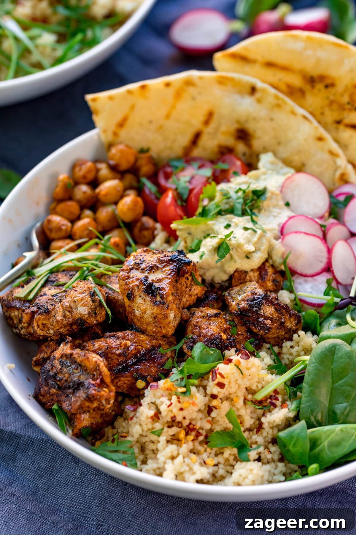 Spicy Chicken Power Bowl with Avocado & Lime Rice 2 spicy chicken, chickpeas, couscous, leaves, radish, hummus and flatbreads in a bowl