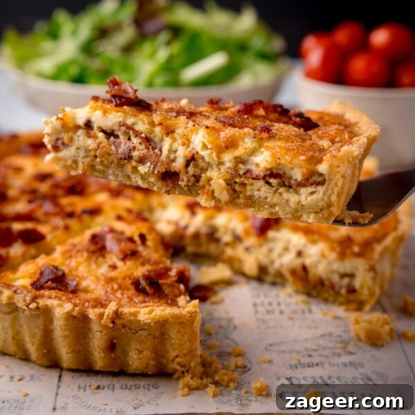 Chicken Chorizo Puff Pastry Rolls: Savory Baked Appetizer Recipe 15 A square image of Quiche Lorraine. The quiche is in the centre of the image, a slice of the quiche has been removed and is being shown in the foreground.
