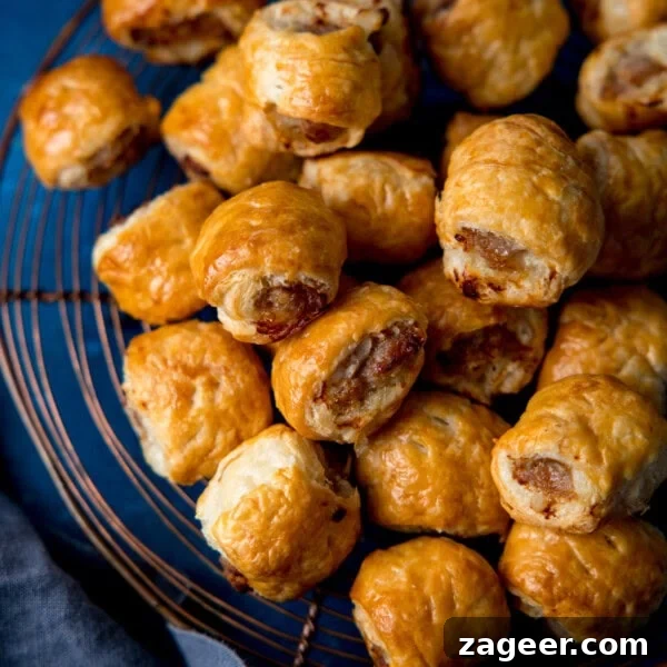 Chicken Chorizo Puff Pastry Rolls: Savory Baked Appetizer Recipe 16 A pile of golden-brown sausage rolls rests on a wire cooling tray, showing flaky pastry and browned meat filling.