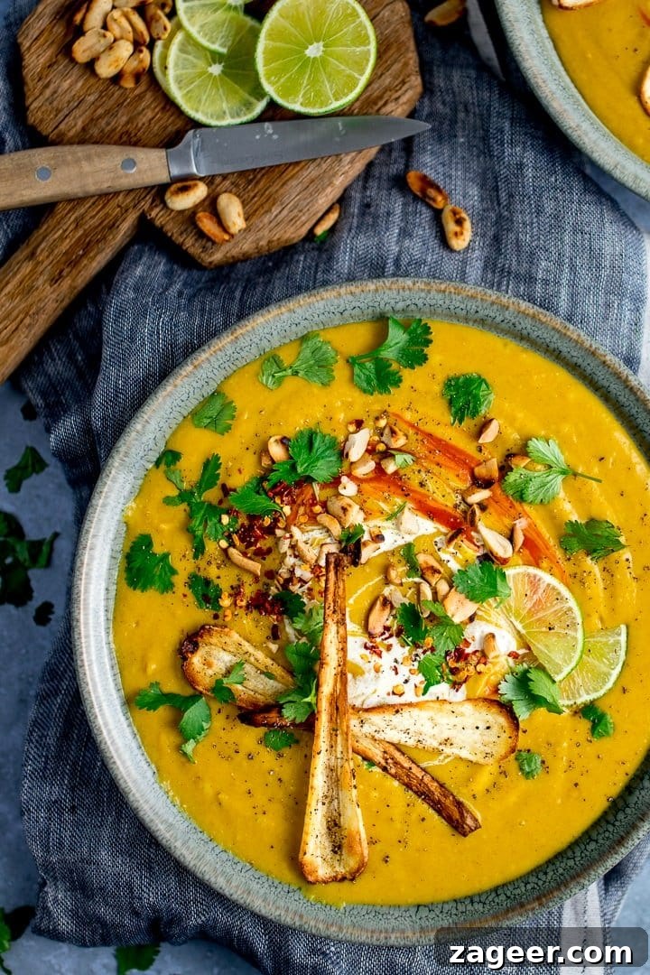 Spicy Parsnip and Sweet Potato Soup Recipe for Cozy Nights 6 Tall image of parsnip and sweet potato soup on blue background. Toppings scattered around an on soup.