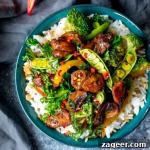 Bowl of sticky chicken stir fry on boiled white rice in green bowl.