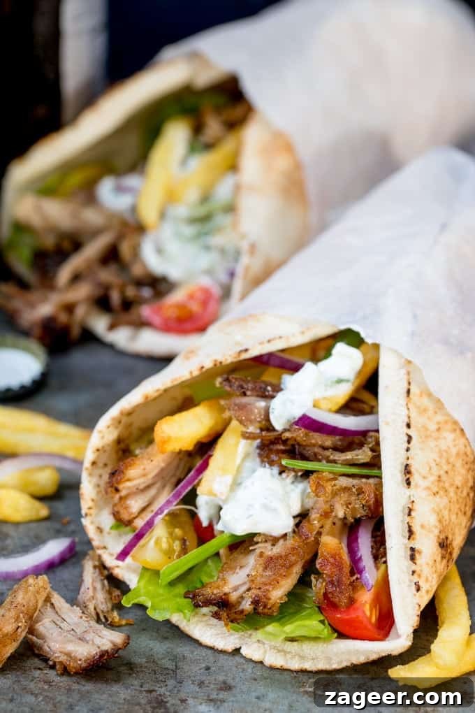 Crispy Pork Gyros Recipe: Greek-Style Sandwich with Tzatziki 7 Pork Gyros in a flatbread with sauce and toppings, being held in a hand